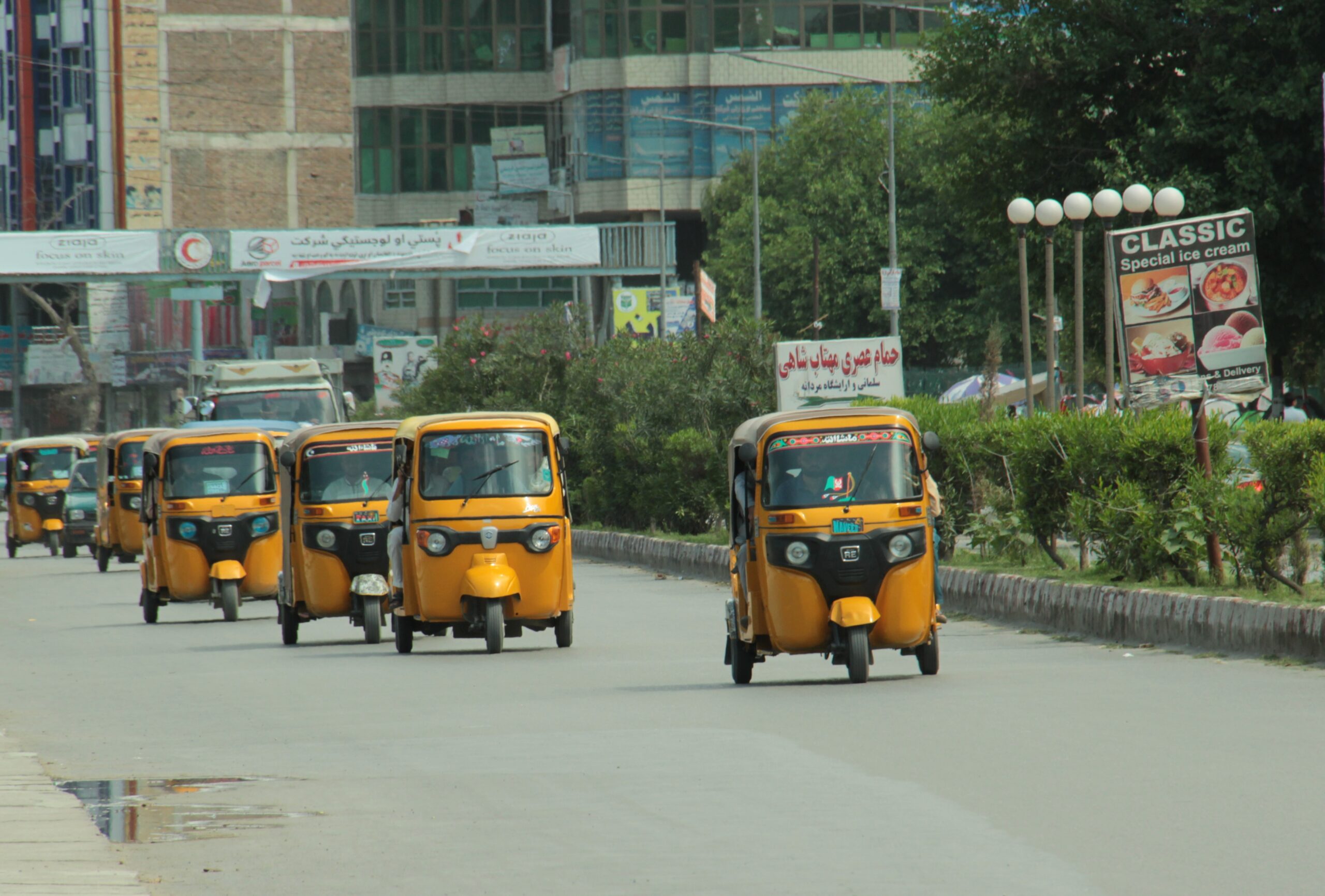 Photograph of small yellow rickshaws with three wheels.