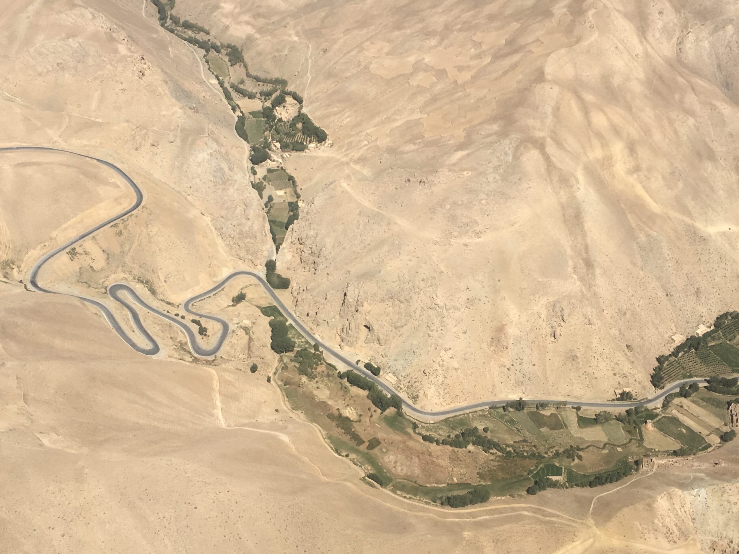 Aerial photography of brown mountains, one road winds through the image.